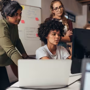 3 pessoas acompanham uma delas que mexe no computador.